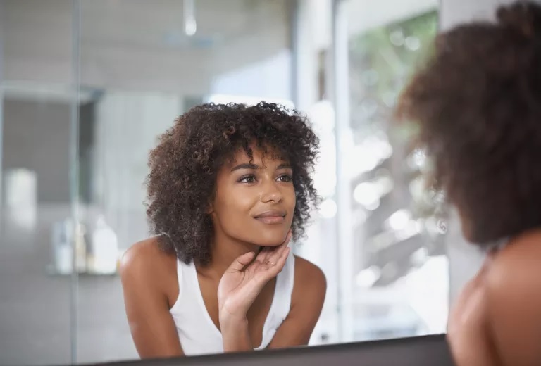 Woman looking at skin in mirror